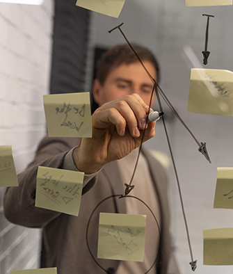 Person-drawing-on-glass-with-post-it-notes