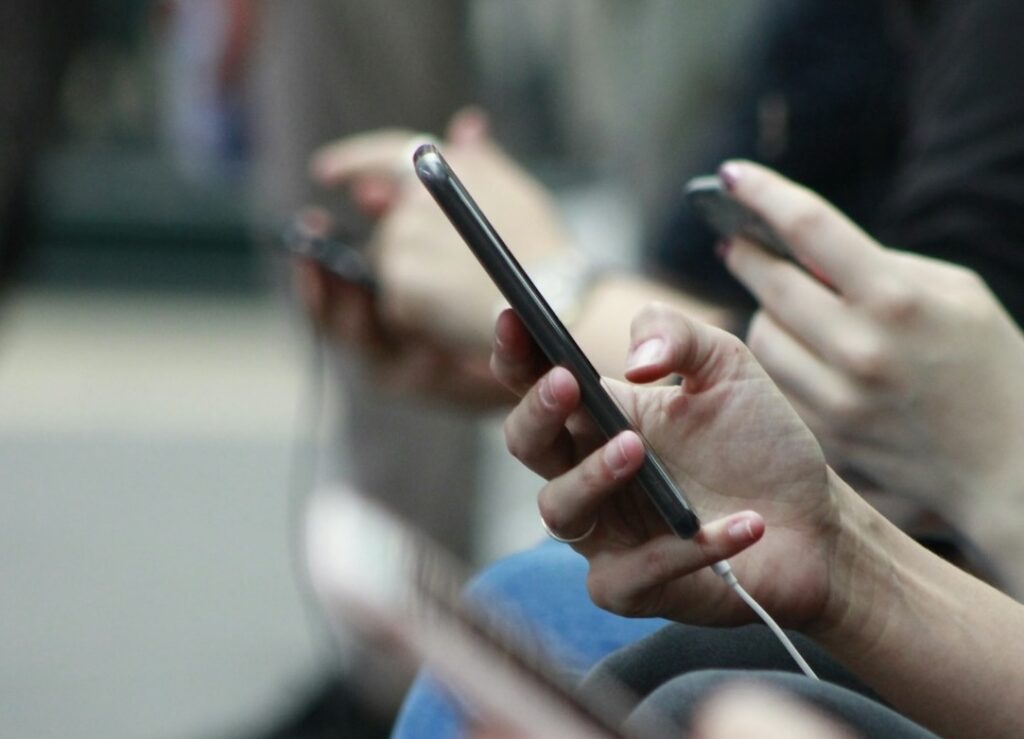 Multiple-people-sitting-side-by-side,-each-looking-at-their-phone