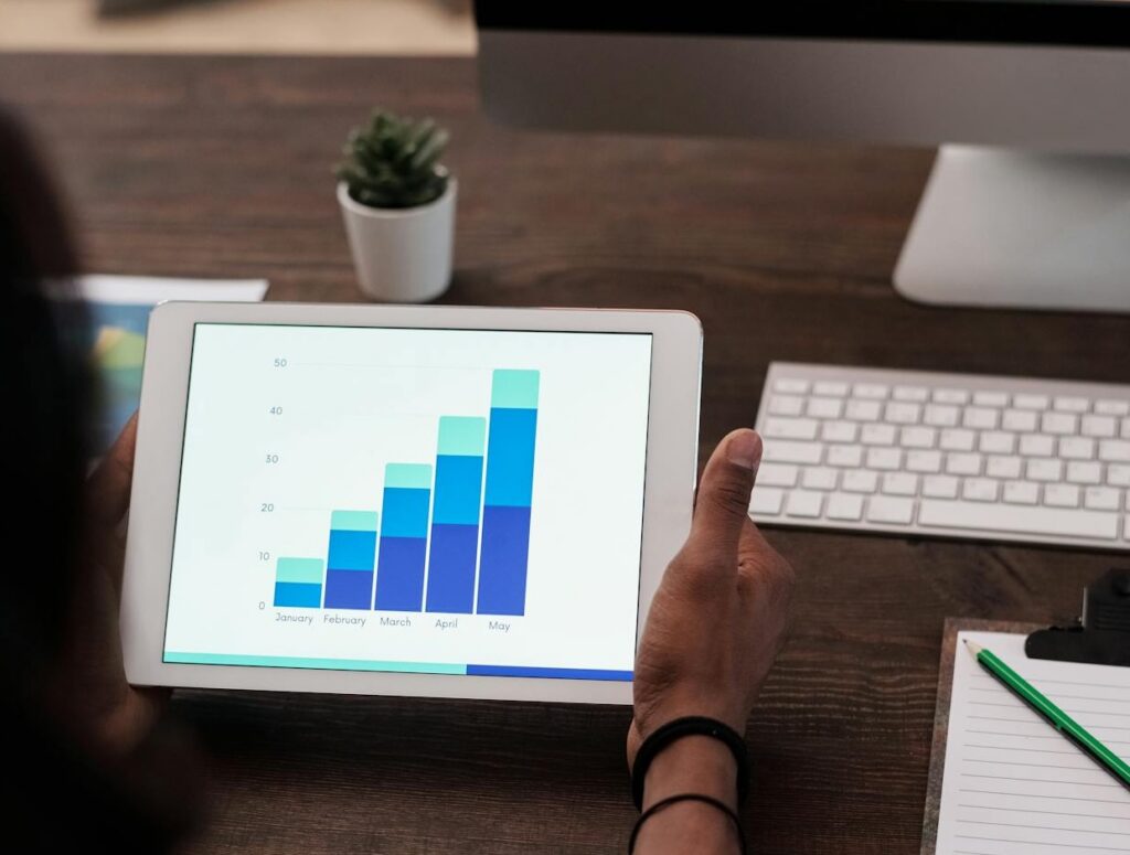 Person holding a tablet displaying a bar chart showing monthly growth data
