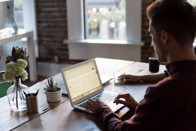 Person-working-on-a-laptop-at-a-wooden-desk